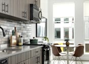 Thumbnail 2 of 19 - A modern kitchen with a dining table and chairs.
