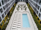 Thumbnail 17 of 19 - A pool surrounded by lounge chairs and greenery on a rooftop.
