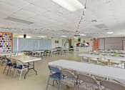 Thumbnail 9 of 12 - A large room with tables and chairs is set up for an event.