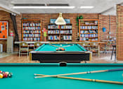 Thumbnail 11 of 12 - A pool table with a green cloth and a yellow cue stick.