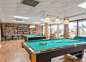 Thumbnail 12 of 12 - A pool table in a room with a brick wall and a bookshelf.