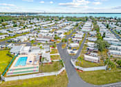 Thumbnail 2 of 12 - A bird's eye view of a residential area with a swimming pool and a road.