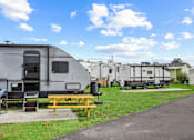 Thumbnail 4 of 12 - A grey RV is parked next to a picnic table.