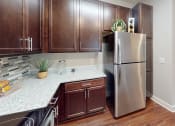 Thumbnail 4 of 39 - a kitchen with dark wood cabinets and white countertops at The Bend Arbordale, Williamsburg, 23188