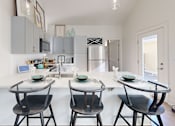 Thumbnail 2 of 40 - a kitchen with a white counter top and three stools at The Cottages at Old Monrovia Apartment , Alabama