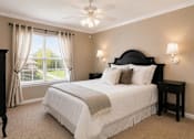 Thumbnail 6 of 36 - A bedroom with a large bed and a window with curtains.