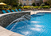 Thumbnail 22 of 36 - A pool with a waterfall feature in the middle of it.