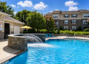 Thumbnail 21 of 36 - A swimming pool with a waterfall feature in the middle of it.