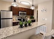 Thumbnail 2 of 36 - A kitchen with granite countertops and a stainless steel refrigerator.