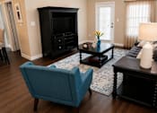 Thumbnail 5 of 36 - A living room with a blue chair and a black cabinet.
