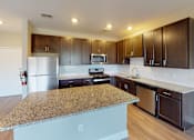Thumbnail 17 of 33 - a kitchen with dark wood cabinets and an island with granite countertops at The Landing Apartment , Hazlet, NJ