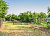 Thumbnail 23 of 29 - the yard is fenced in with a playground and trees at Diamond  Trail Apartments, Oklahoma City, OK