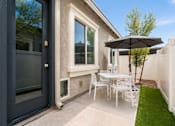 Thumbnail 8 of 16 - A patio with a table and chairs and an umbrella.