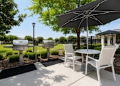 Thumbnail 14 of 16 - A patio with a table, chairs and an umbrella.