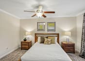 Thumbnail 16 of 32 - A bedroom with a large bed, two nightstands, and a ceiling fan.