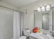 Thumbnail 32 of 32 - A bathroom with a white toilet, sink, and shower curtain.
