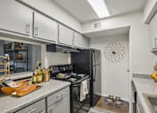 Thumbnail 11 of 32 - A kitchen with black appliances and white cabinets.