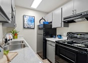 Thumbnail 2 of 27 - Kitchen with stainless steel appliances and a stove and refrigerator at Verde Apartments in Tucson, 85719