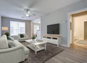 Thumbnail 5 of 21 - A living room with a white couch, a white coffee table, and a flat screen TV.