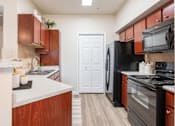 Thumbnail 4 of 15 - Kitchen with black appliances and wood cabinets at Park Hudson Place Apartments, Bryan, Texas