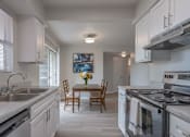 Thumbnail 1 of 11 - A kitchen with a table and chairs in the middle.