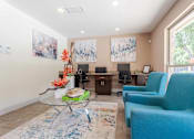 Thumbnail 11 of 26 - A living room with a blue chair and a glass table.