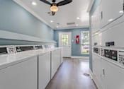 Thumbnail 20 of 26 - A laundry room with a row of washers and dryers.