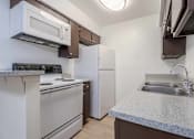 Thumbnail 5 of 26 - A kitchen with a stove, oven, refrigerator, and microwave.