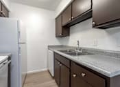Thumbnail 18 of 26 - A kitchen with brown cabinets and a white refrigerator.