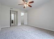 Thumbnail 7 of 26 - A room with a ceiling fan and carpeted floor.