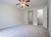 Thumbnail 21 of 26 - A room with a ceiling fan and carpeted floor.