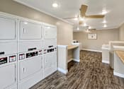 Thumbnail 9 of 17 - A laundry room with a row of washers and dryers.