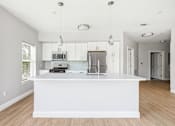 Thumbnail 80 of 87 - A modern kitchen with a white island and wooden floors.