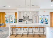 Thumbnail 62 of 87 - A modern kitchen with a white island and stools. at Axis at Lakeshore, Bridgewater, Massachusetts