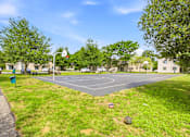 Thumbnail 29 of 52 - A basketball court is surrounded by grass and trees.