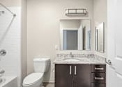 Thumbnail 77 of 87 - A bathroom with a toilet, sink, and mirror.