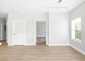Thumbnail 68 of 87 - A room with a white door, a window with blinds, and a rug on the floor.