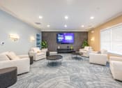 Thumbnail 8 of 40 - A spacious waiting room with a TV screen, comfortable seating, and a coffee table.
