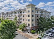 Thumbnail 1 of 40 - A large apartment complex with a parking lot in front.