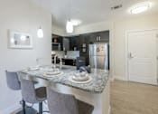 Thumbnail 21 of 40 - A kitchen with a granite countertop and grey chairs.