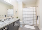 Thumbnail 26 of 40 - A bathroom with a sink, toilet, and a shower curtain.