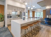 Thumbnail 6 of 40 - A modern kitchen with a white island and wooden stools.