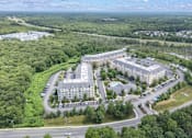Thumbnail 3 of 40 - A large building complex surrounded by trees and a parking lot.