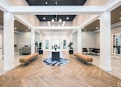Thumbnail 2 of 40 - A spacious lobby with a wooden floor and white columns.