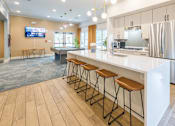 Thumbnail 7 of 40 - A modern kitchen with a long white counter and bar stools.