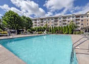 Thumbnail 16 of 40 - A swimming pool in front of a large apartment building.
