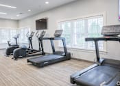 Thumbnail 13 of 40 - A gym with treadmills and a television mounted on the wall.