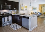 Thumbnail 12 of 35 - A modern kitchen with dark brown cabinets and a white island at Axis at Lakeshore Apartments, Bridgewater