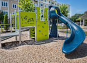 Thumbnail 33 of 35 - A playground with a slide and a sign that says at Axis at Lakeshore Apartments, Bridgewater, Massachusetts