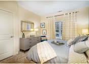 Thumbnail 20 of 35 - A bedroom with a bed, nightstand, and a window with curtains at Axis at Lakeshore Apartments, Massachusetts